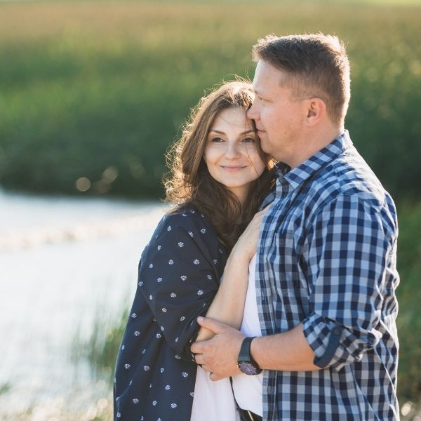 loving couple standing in field embracing