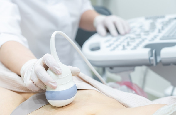 Clinician performing an abdominal ultrasound scan during a medical examination.