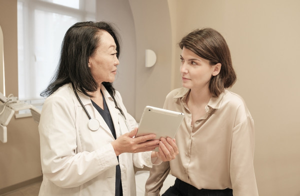 Doctor discussing care with a patient in a clinic while holding a tablet.