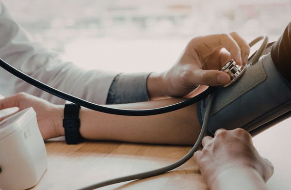 Clinician checking a patient’s blood pressure during a consultation.