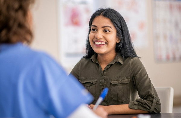 Smiling patient speaking with a healthcare professional during a clinic appointment.